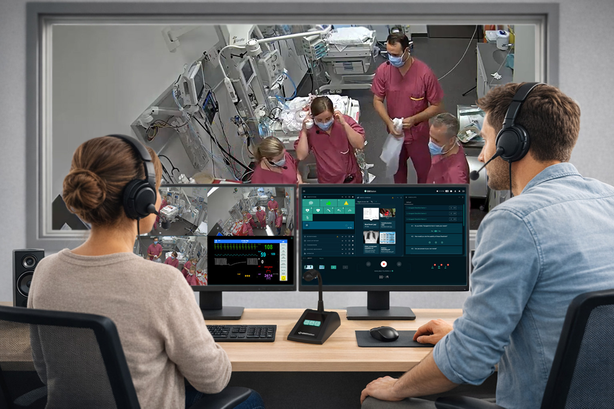 Simulation instructors managing a live medical training scenario using a multi-screen control system