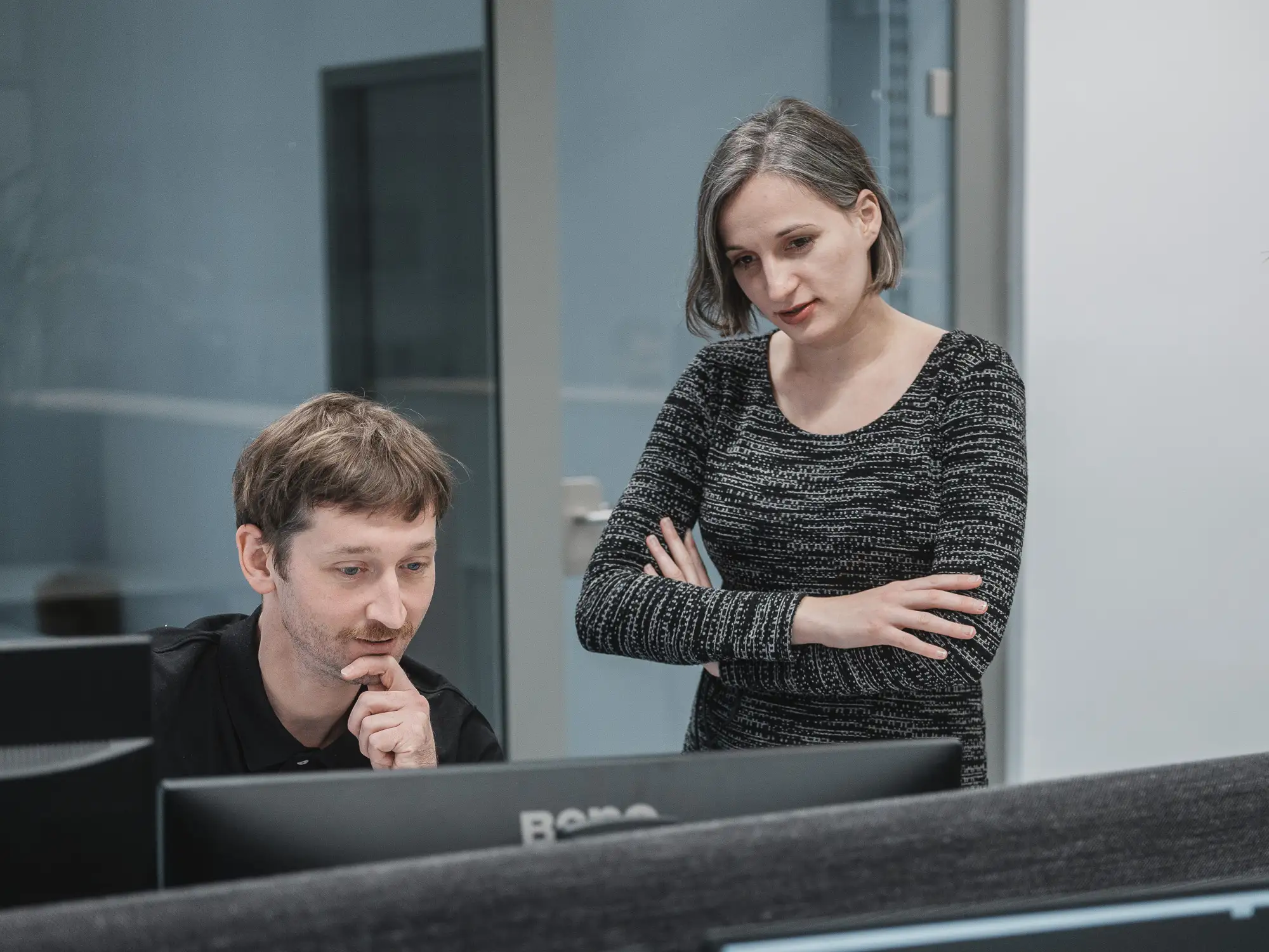 Two SIMStation team members working together at a computer in a modern office environment.